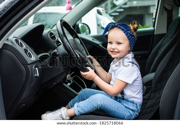 Little girl pretends to drive a car. Concept\
photo of children education, learning , drive a car,funny, happy,\
play, happiness, car\
insurance