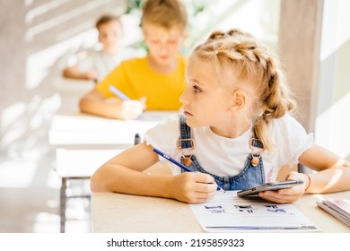 Little Girl Primary School Girl Student With Two Braids In Classroom Cheating During Classwork At Classroom. Attendancy, Academic Performance Concept.