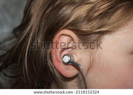 Little girl in profile with an earpiece.