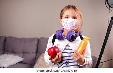 Little Girl Protective Mask. Got Ready To Go To School. Schoolgirl With Lunch In Hand, Books For The School Day. Education, Learning Concept. New Realities Of Education. Free Space For Text