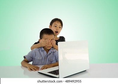 Little Girl Protects His Brother From Watching Inappropriate Content While Using A Computer. Internet Safety For Kids Concept. Toned Image With Selective Focus