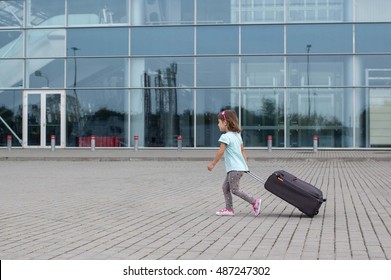 Little girl pulls a suitcase and goes to airport