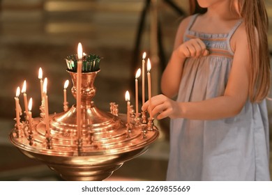 A little girl puts a candle in church. Orthodoxy