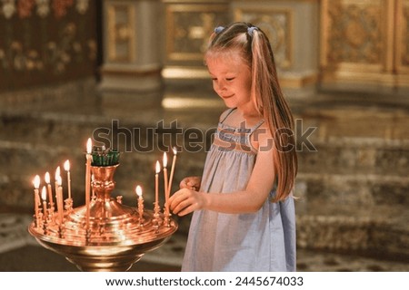little girl puts a candle in church. Orthodoxy and children