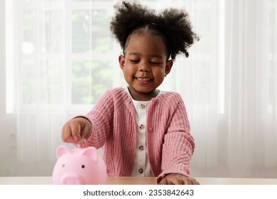 Little girl putting coin of cash into ceramic piggy bank - Shutterstock ID 2353842643