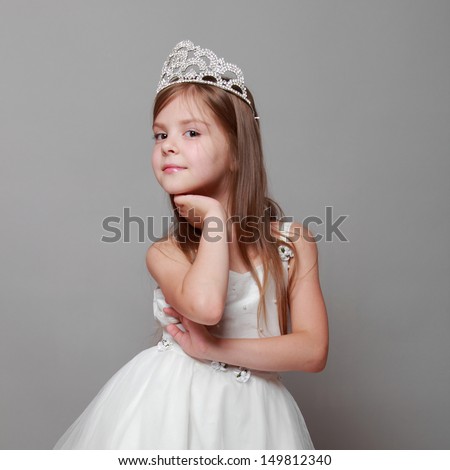 Little girl is putting on a diamond diadem on Beauty and Fashion/Young princess smiling and posing for the camera