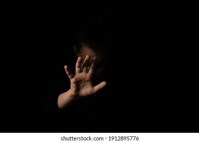 little girl with a raised hand on a black background