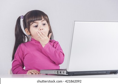 Little Girl Reacts While Using A Laptop. Internet Safety Concept. Toned Image With Selective Focus