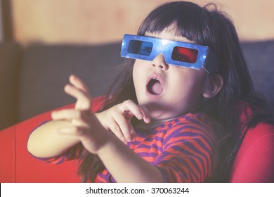 Little girl reacts while watching a 3D movie. Vintage effect image with shallow depth of field