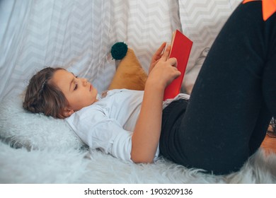 Little girl reading a book in her room in a tent. - Shutterstock ID 1903209136