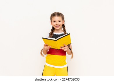 A little girl is reading a book on the German language. Courses on teaching German to children.
