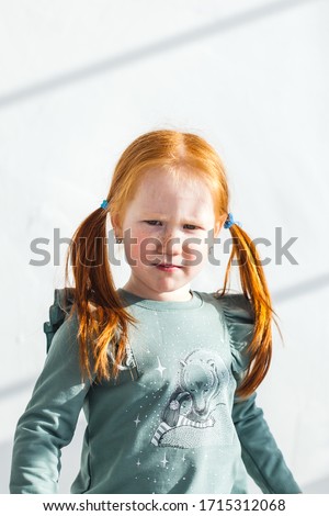 a little girl with red hair and freckles frowns, not happy, angry, offended, did not give a toy or cartoon, emotions on the face of the child