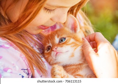 Little girl with a red kitten in hands close up.  Best friends. Interaction of children with pets.