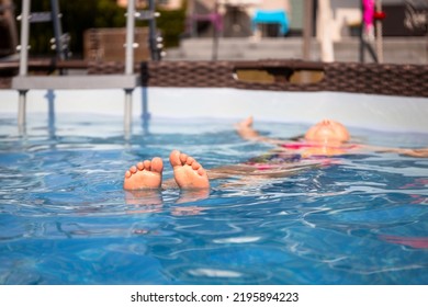 A Little Girl Relaxes In The Pool By Swimming On Her Back