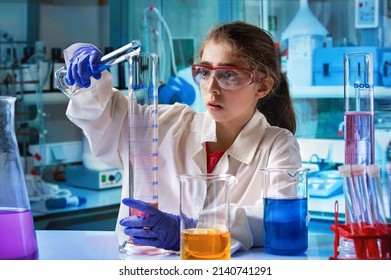 Little Girl Researcher Learning In Experiment With Test Tubes In The Science Chemistry Class. Girl Student Scientist Mixing Colored Liquids With Chemistry Material In School Science Lab