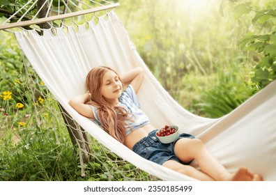 A little girl rests in a hammock and eats cherries in the summer.  Summer in the village.  - Powered by Shutterstock