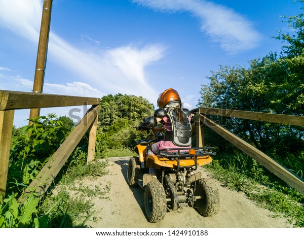 The little girl\
rides a quad bike. A mini quad bike is a cool girl in a helmet and\
protective clothing. Electric quad bike electric car for children\
popularizes green\
technology