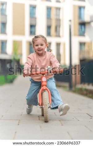 Little girl riding balance bike in the courtyard of the residence in Prague, Europe. High quality photo