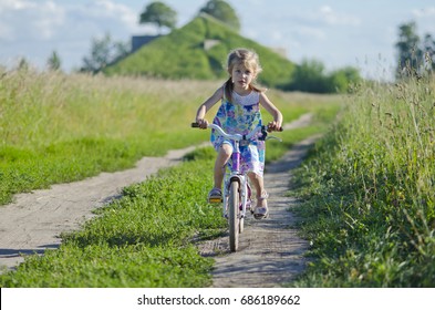 Little girl riding bike in the field. 