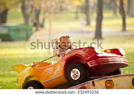 Little Girl Riding a Car In Amusement Park Outdoor