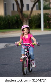 A Little Girl Riding Her Bike In The Neighborhood.