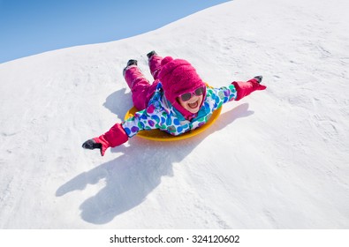 little girl riding on snow slides in winter time