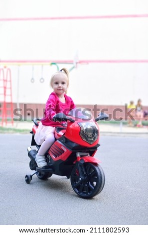 Little girl riding a toy motorcycle on the street