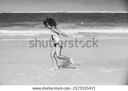 Little girl rins over shore water at the beach, black and white photo