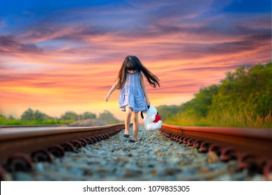 little girl run away from home, walking on railway alone, upset with parent and disappoint mind, sadly walikng with dollmate
