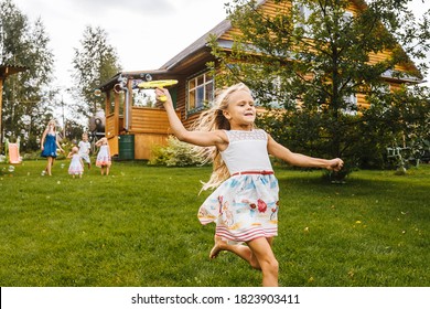 Little girl run with blowing soap bubbles. Backyard, family on background.