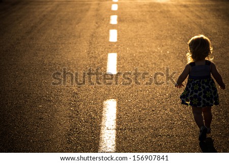 Little girl running away on the road ahead