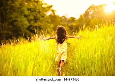 Little girl running on meadow with sunset - Shutterstock ID 144993463