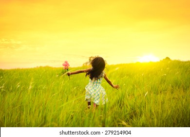 Little Girl Running On Meadow With Sunset