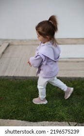 Little Girl Is Running Outside On The Grass. Cute Baby Girl. 