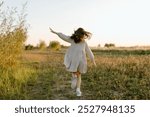 Little girl running through the field. Happy childhood concept. Cheerful child in meadow in sun. summer joy outdoors