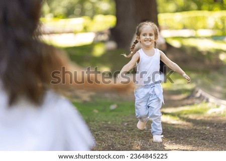 Little girl running towards her mother in the park