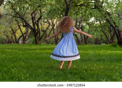 Little Girl Runs Barefoot On The Grass. Happy Child On A Hot Summer Day.