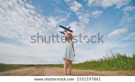 A little girl runs and launches a paralon toy airplane.