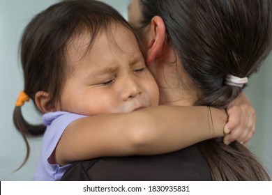 A Little Girl Sad And Afraid Holding Her Mother To Feel Comtort And Protection.