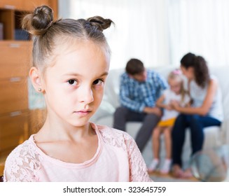 Little girl sad because of jealous younger sister to parents. focus on girl