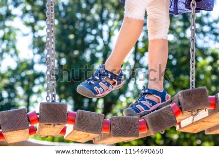 Little girl with sandal walking over bridge.