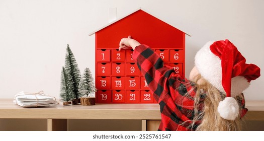 Little girl in Santa hat near table with Christmas advent calendar and letters at home - Powered by Shutterstock