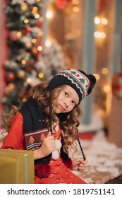 little girl in a santa hat on a snowy street - Shutterstock ID 1819751141