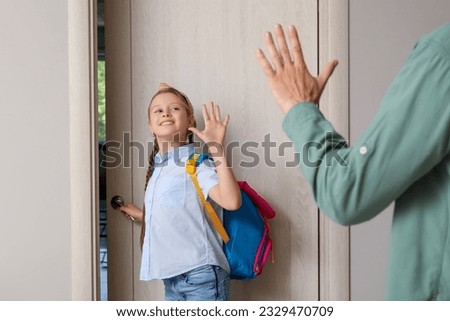 Little girl saying goodbye to her father before going to school in hall
