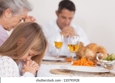 Little Girl Saying Grace With Family Before Thanksgiving Dinner