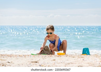 Little Girl School Age Play With Sand And Colorful Toys At Summer Sea Beach Background, Happy Childhood And Family Vacation