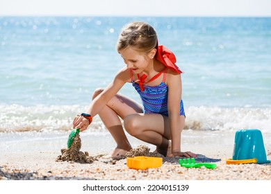 Little Girl School Age Play With Sand And Colorful Toys At Summer Sea Beach Background, Happy Childhood And Family Vacation