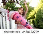 Little girl  with school satchel on first day to school, holding school cone with gifts