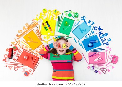 Little girl with school supplies, books, drawing and painting tools and materials. Happy back to school student. Art and crafts for kids. Child learning rainbow colors, alphabet letters and numbers. - Powered by Shutterstock