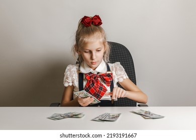 A Little Girl In A School Uniform Is Counting Money - Hundred-dollar Bills. Teaching Children Financial Literacy.